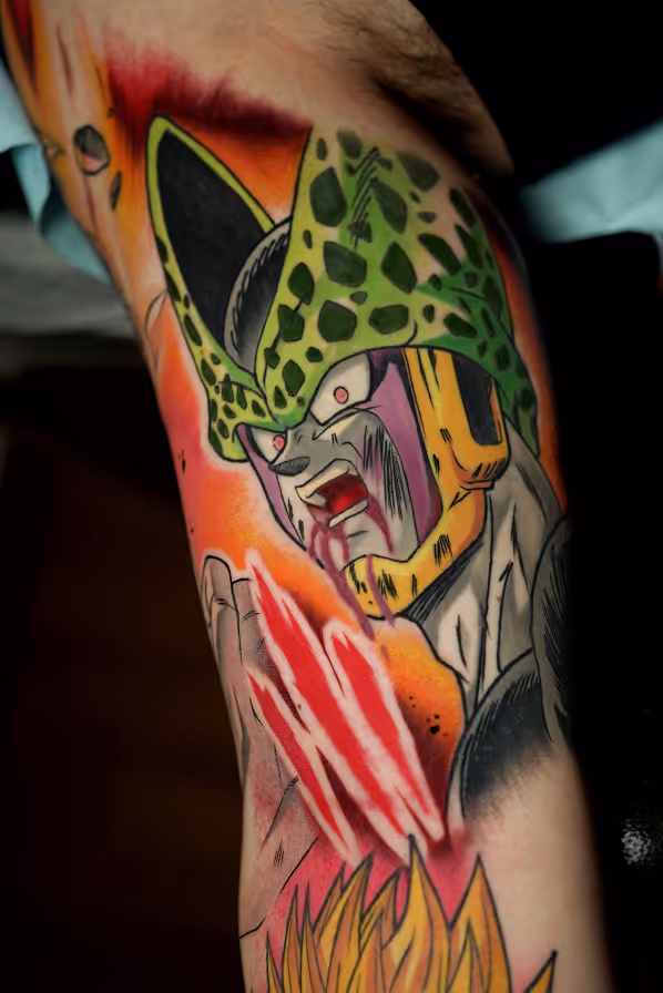 Tattoo of Cell, a character from Dragon Ball Z, with an intense expression, green spotted head, and yellow-orange background on a person's arm.