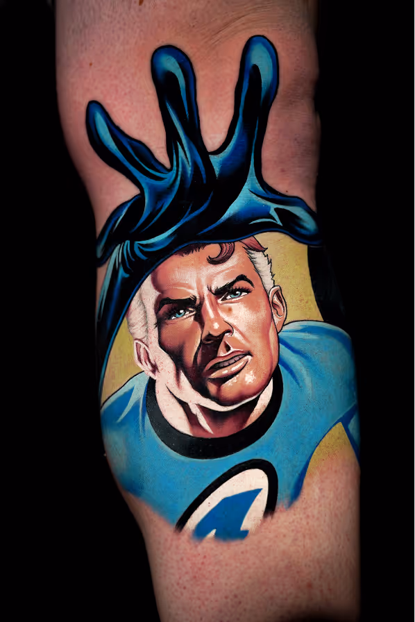 Realistic tattoo of Mr. Fantastic from the Fantastic Four, reaching forward with an extended arm and wearing a blue suit with the number 4 emblem.