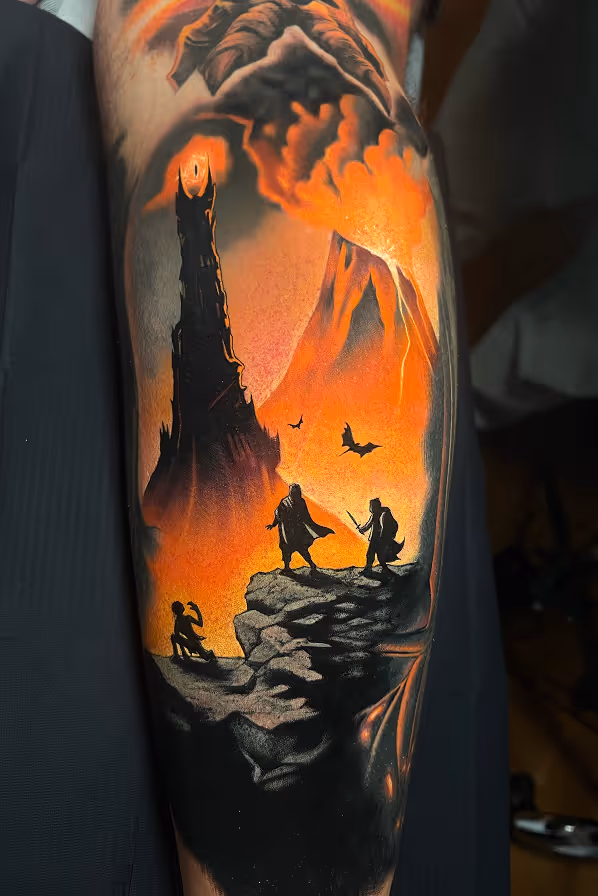 Tattoo of a fiery volcanic landscape with the dark silhouette of Sauron's tower, flying bats, and three figures on rocky terrain, inspired by Lord of the Rings.