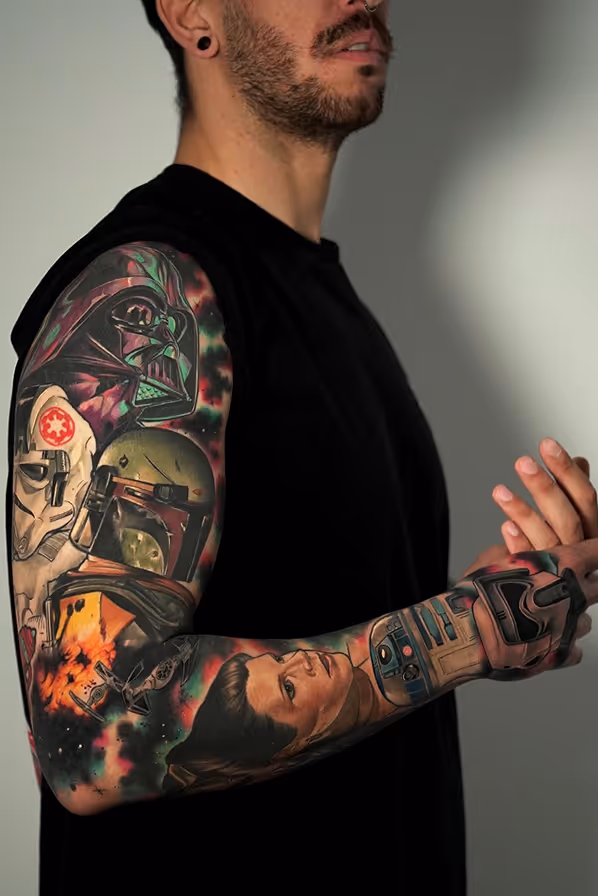 Man with full sleeve tattoo featuring Star Wars characters Darth Vader, Boba Fett, Princess Leia, R2-D2, and stormtrooper helmet, with a space background.